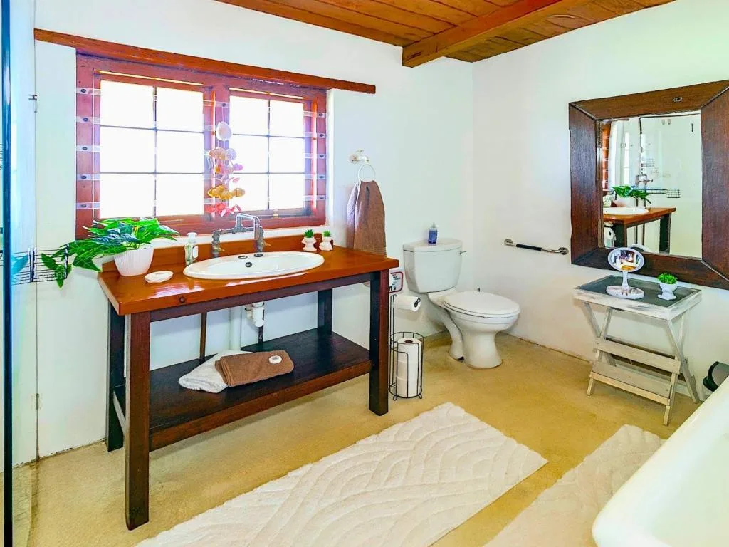 Spacious bathroom with wooden vanity, sink, toilet, and large mirror