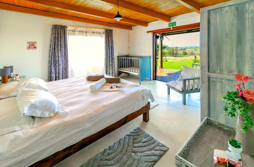 Spacious bedroom with wooden beams, double bed, and open doors to garden views