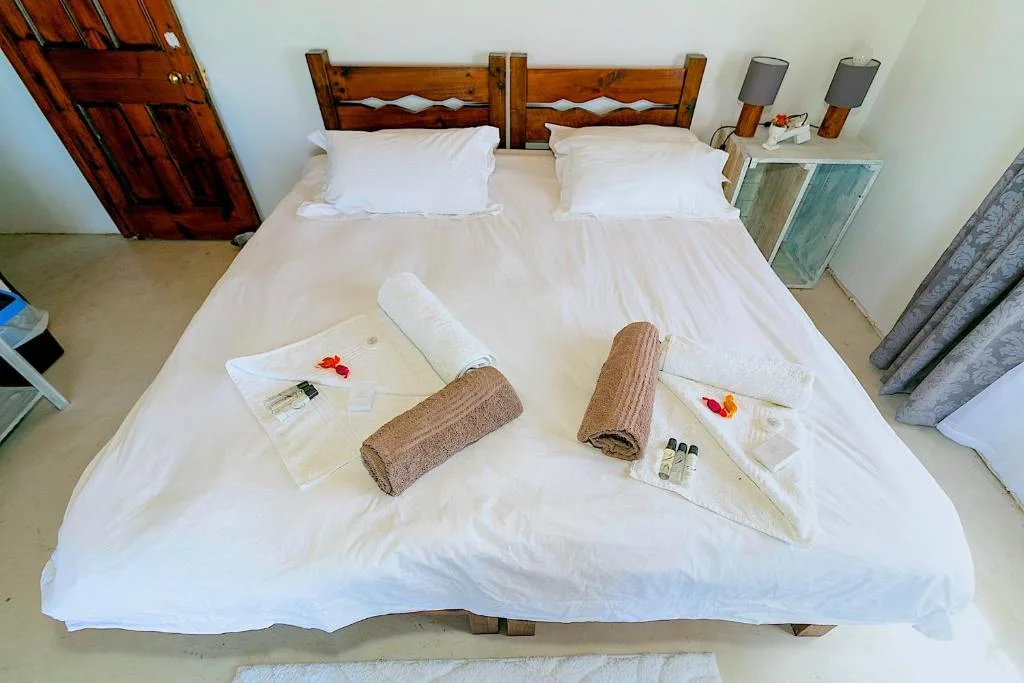 Spacious double bedroom with wooden headboard and welcome amenities