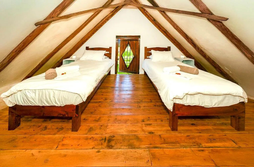 Rustic attic bedroom with two wooden beds and exposed beams