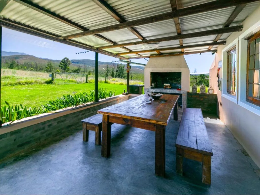Covered outdoor braai area with wooden dining table and mountain views