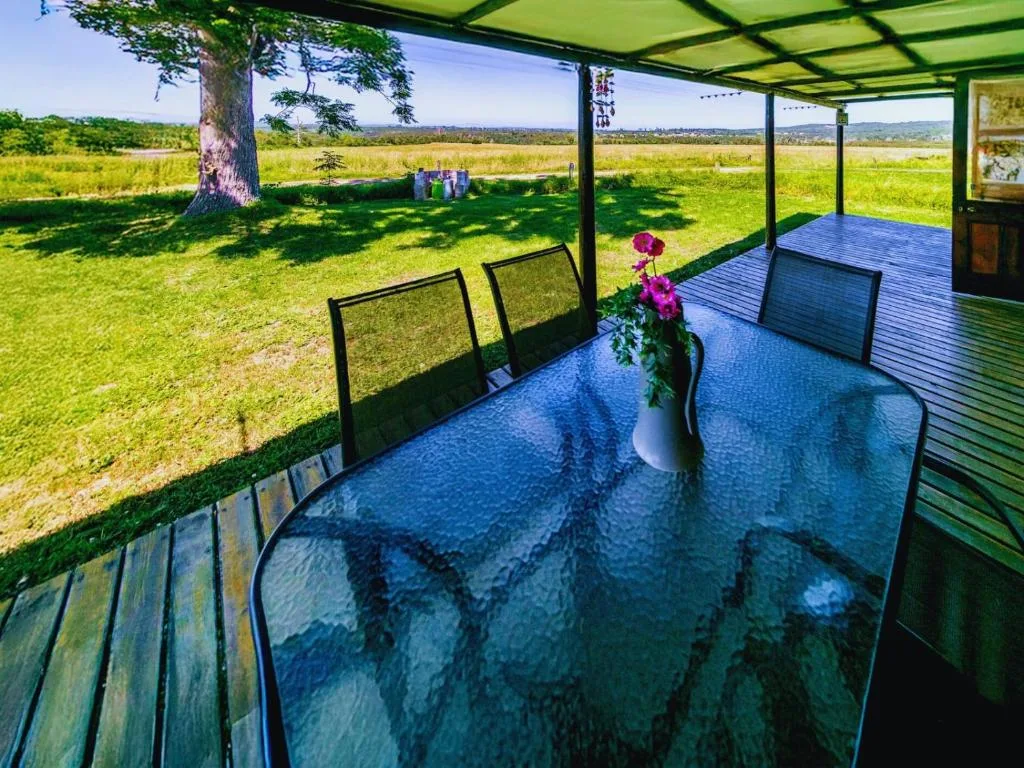 Covered deck with dining table overlooking expansive green fields and mountains