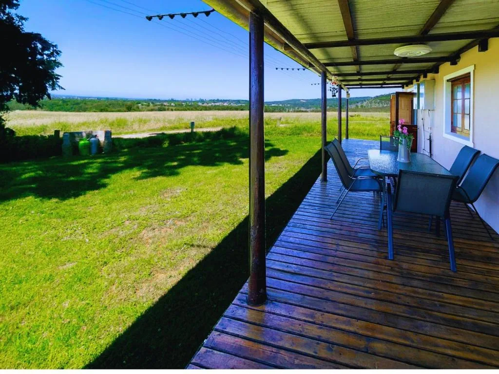 Covered wooden deck with dining table overlooking green pastoral landscape