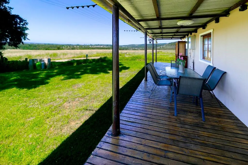 Covered wooden deck with dining table overlooking green garden and distant valley views