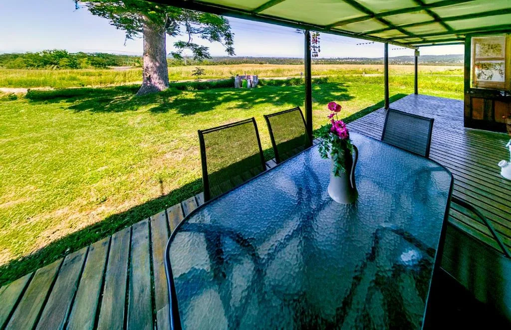 Covered patio with dining table overlooking expansive green gardens and countryside