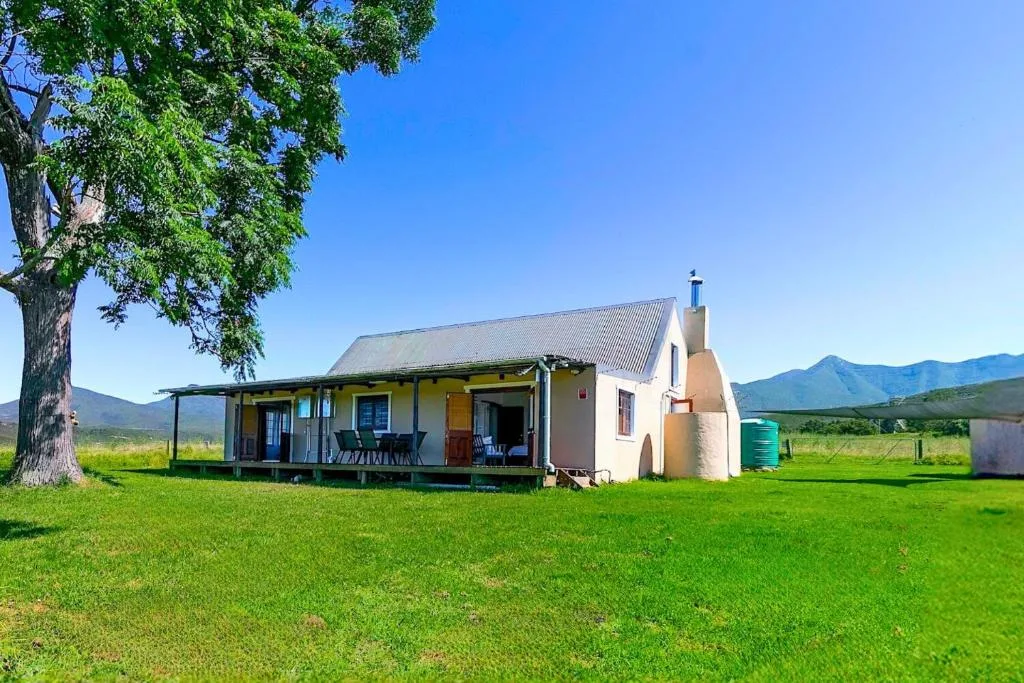 Charming cottage with covered deck and mountain views, set on green grounds
