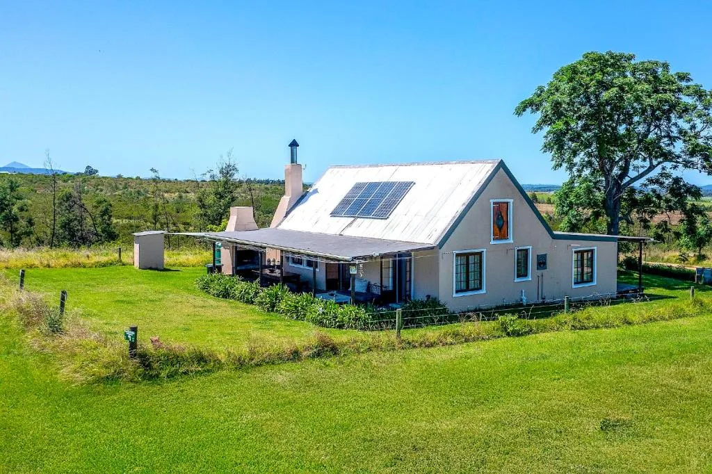 White cottage with blue trim and solar panels on green grounds