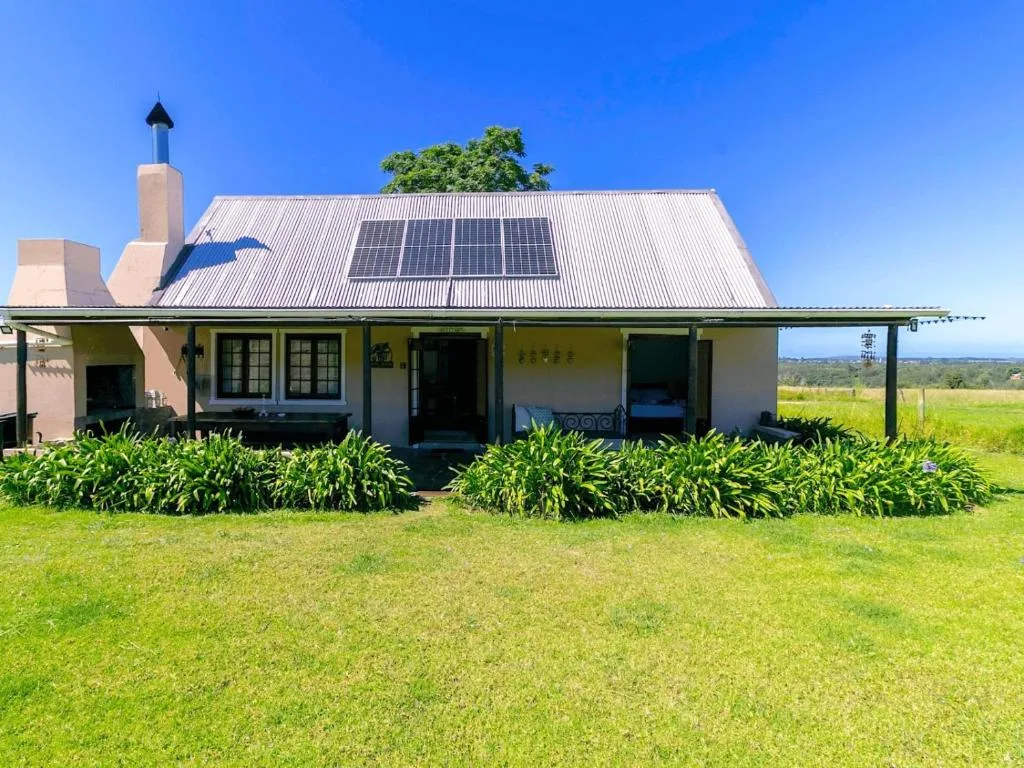 Modern farmhouse with solar panels, veranda, and expansive green gardens
