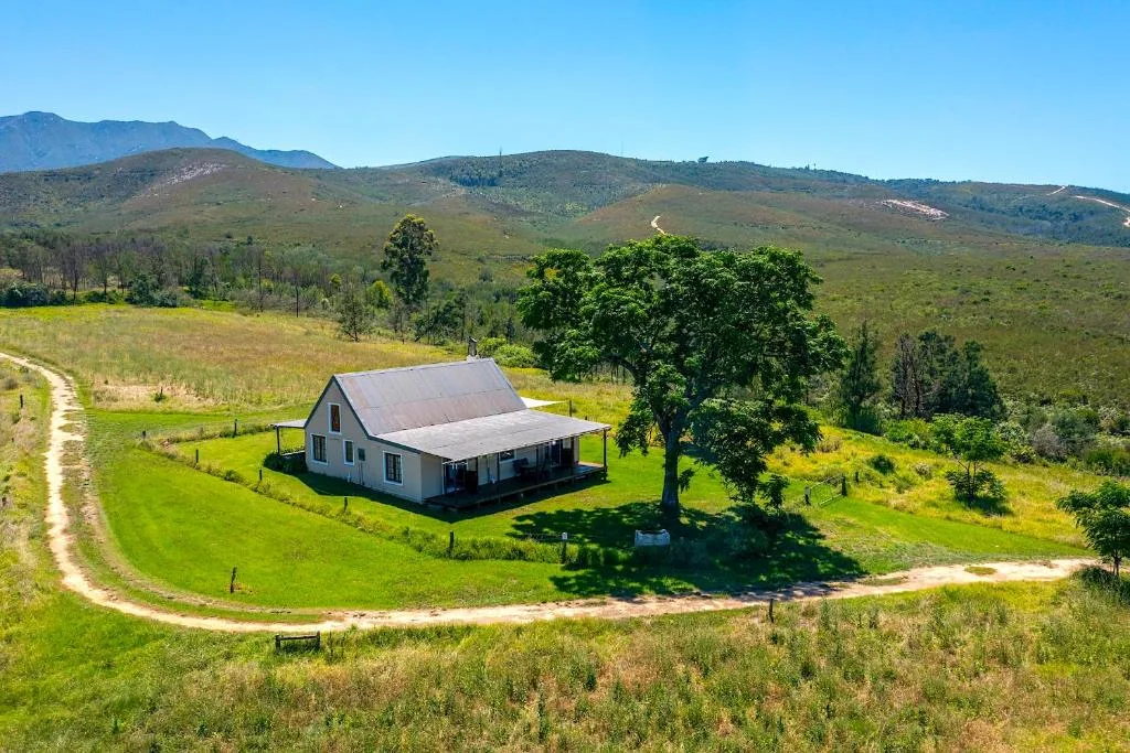 Charming white cottage nestled in lush green valley with mountain views