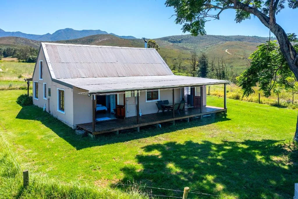 White cottage with corrugated iron roof and front porch in lush green valley