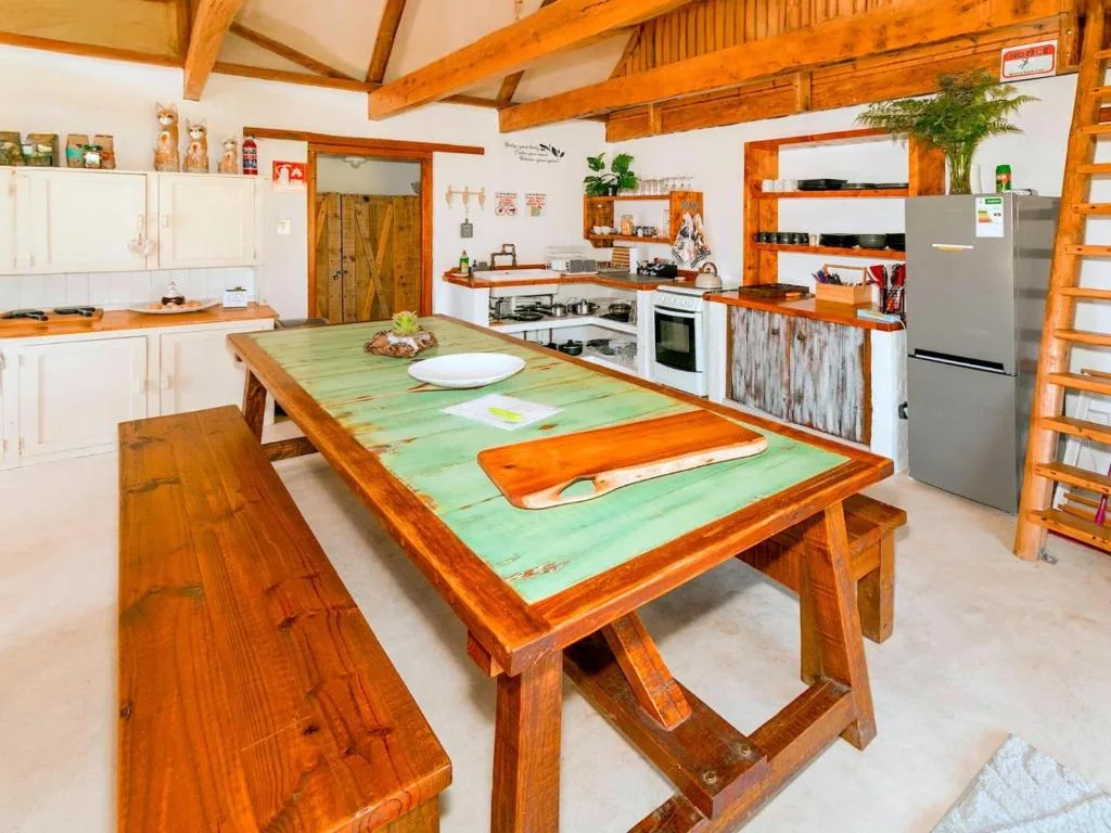 Spacious kitchen with wooden beams, green dining table, and stainless steel appliances