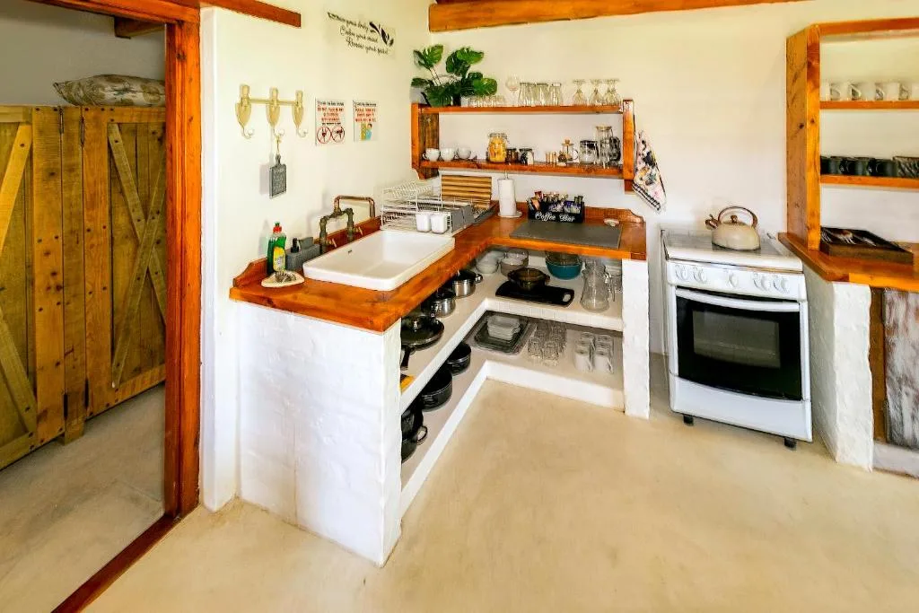 Rustic kitchen with wooden beams, white counters, gas stove, and open shelving