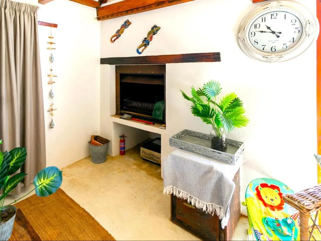 Cozy lounge with fireplace, potted plants, and vintage wall clock decor