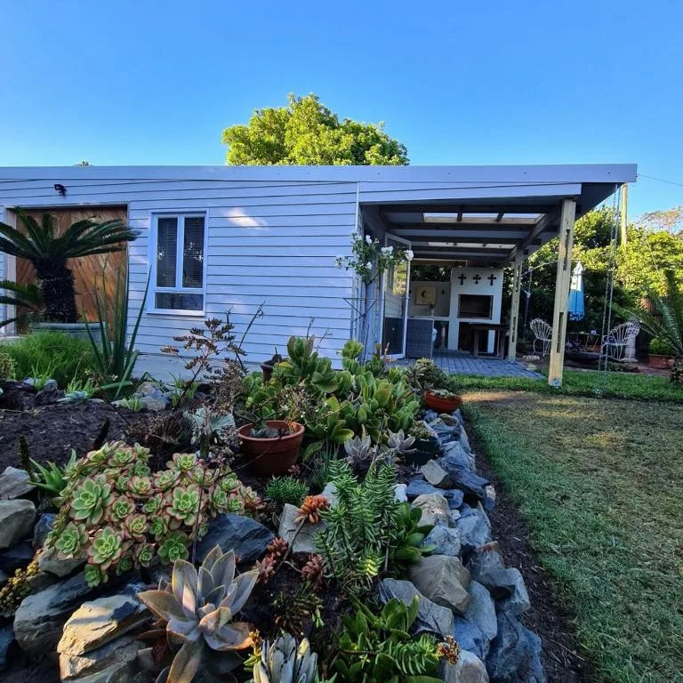 Blue cottage with covered patio and landscaped succulent garden in front