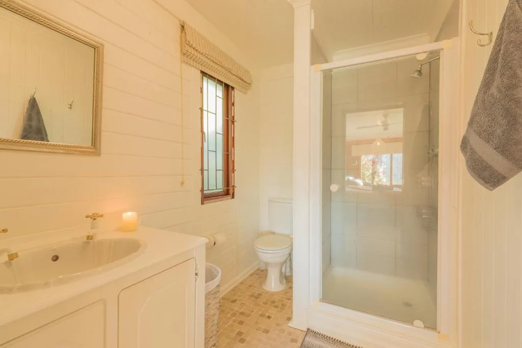 Bright bathroom with vanity sink, toilet, and glass shower enclosure