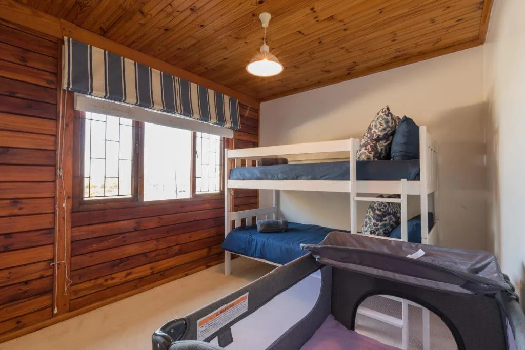 Bright bedroom with white bunk beds and wooden ceiling