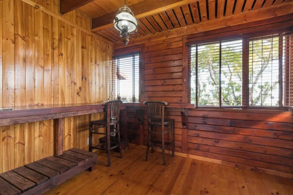 Wooden deck with high chairs and windows overlooking garden views