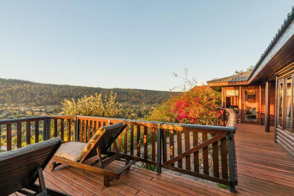 Wooden deck with lounger overlooking forested valley and mountains