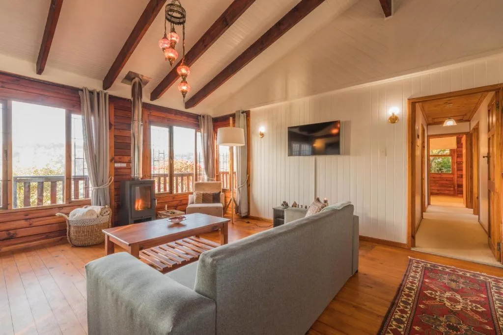 Spacious lounge with fireplace, grey sofa, wooden beams, and mountain views