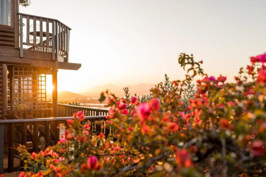 Sunset view over lagoon and mountains from elevated deck with flowering garden
