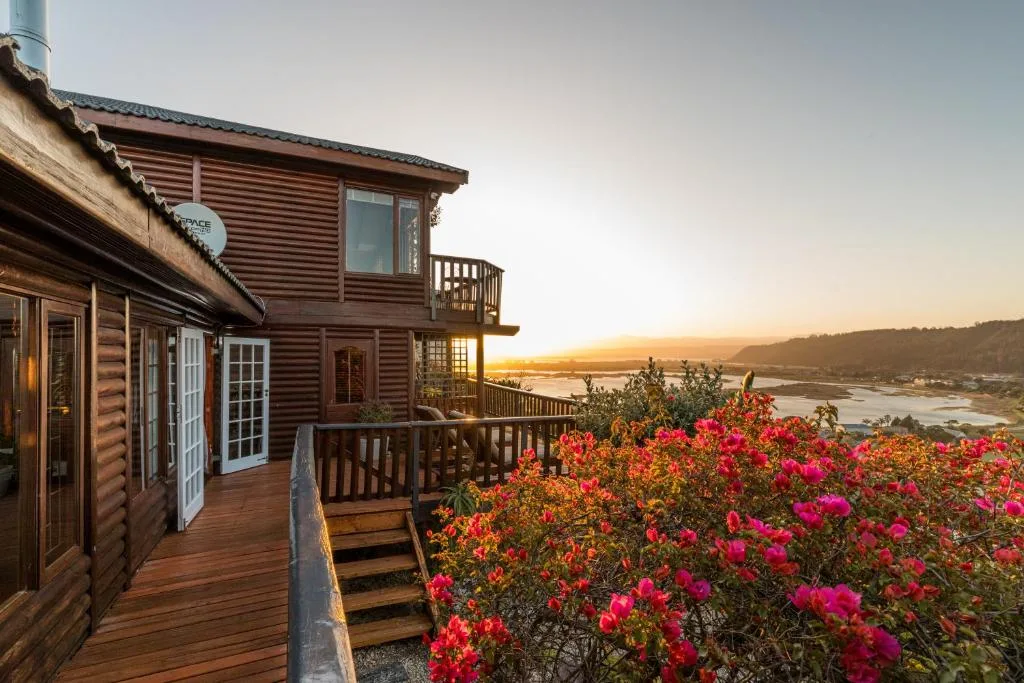Wooden deck with blooming flowers overlooking sunset lagoon and mountains
