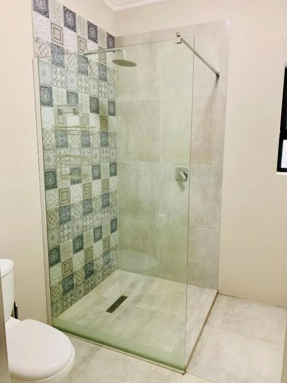 Modern walk-in shower with decorative tiled accent wall and rainfall showerhead