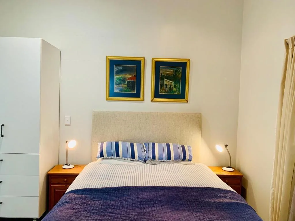 Neatly made bed with striped pillows and warm bedside lighting