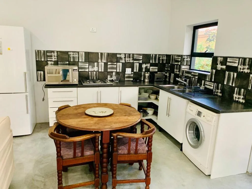 Modern kitchen with white cabinetry, black countertops, and wooden dining table