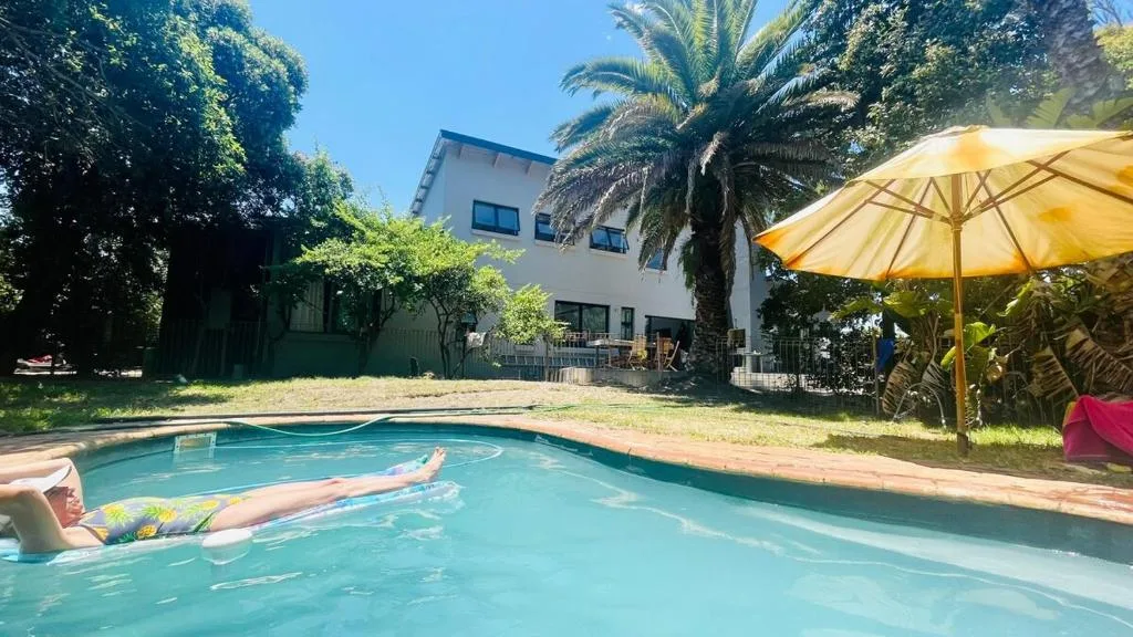 Sparkling swimming pool with guest relaxing, white building and palm trees beyond