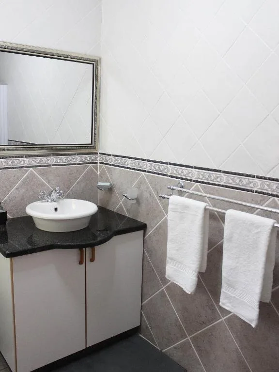 Modern bathroom with round white sink, black countertop, framed mirror, and white towels