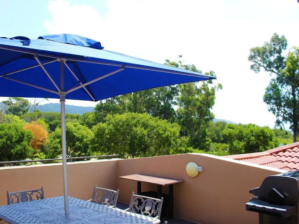 Shaded outdoor patio with blue umbrella overlooking green valley landscape