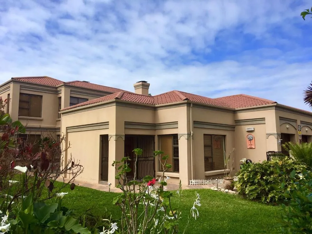 Cream-colored modern house with terracotta tile roof and manicured garden