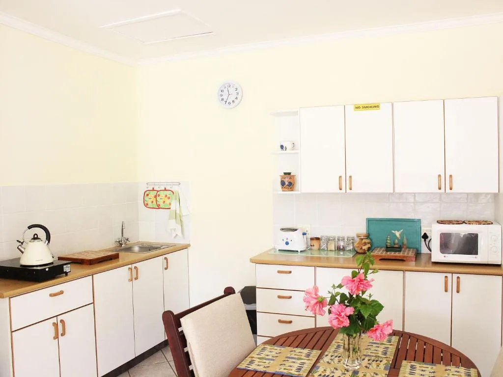 Bright kitchen with white cabinetry, wooden counters, and dining table with pink flowers