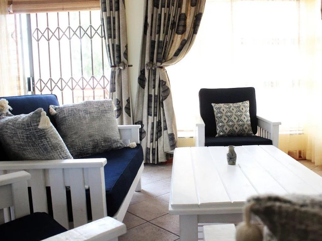 Bright lounge with blue sofa, black armchair, white coffee table, patterned curtains