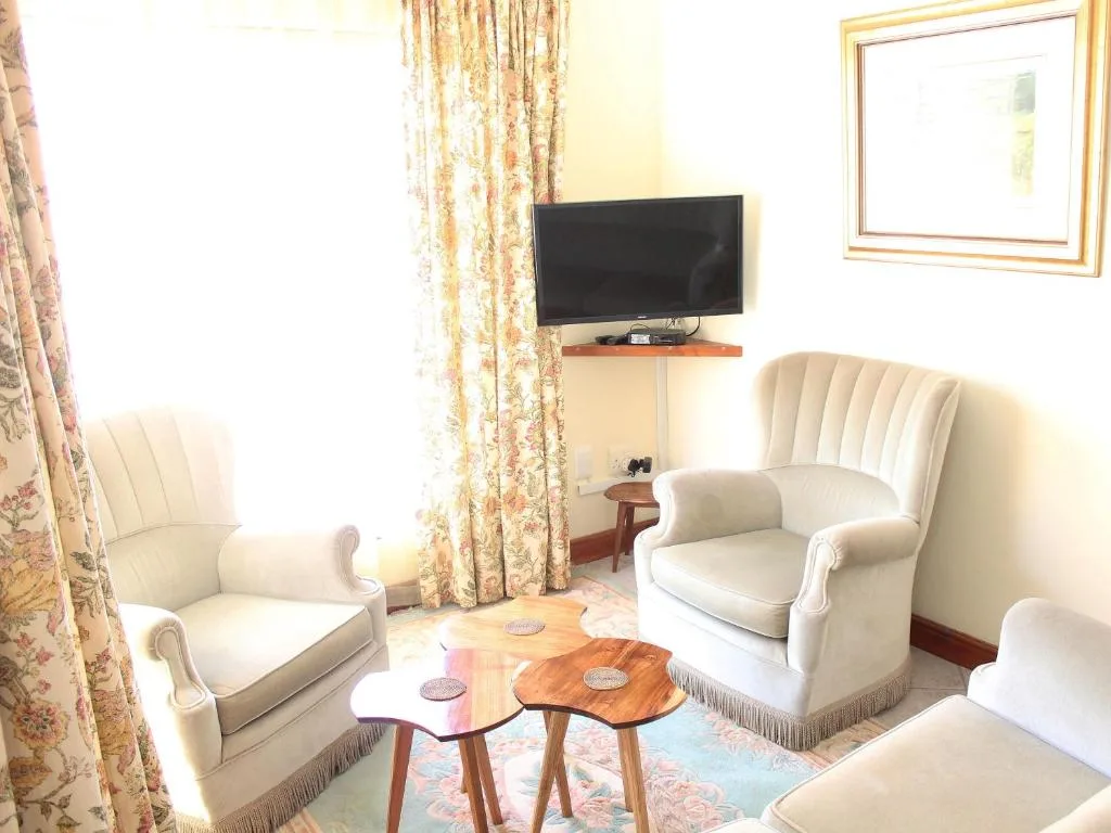 Comfortable cream armchairs arranged around wooden coffee table with wall-mounted television