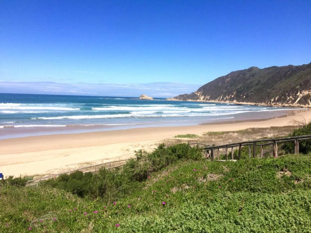 Scenic beach view with waves, sand, cliffs and ocean horizon from property