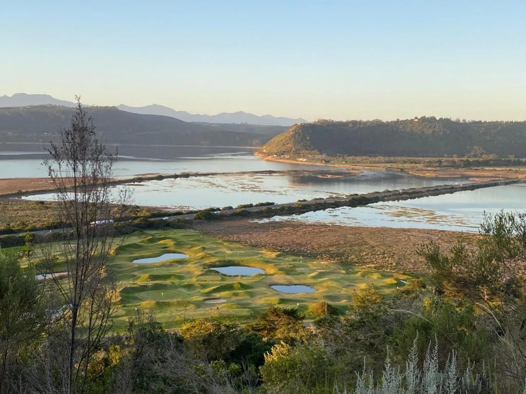 Scenic lagoon landscape with mountains, golf course, and wetlands at sunrise