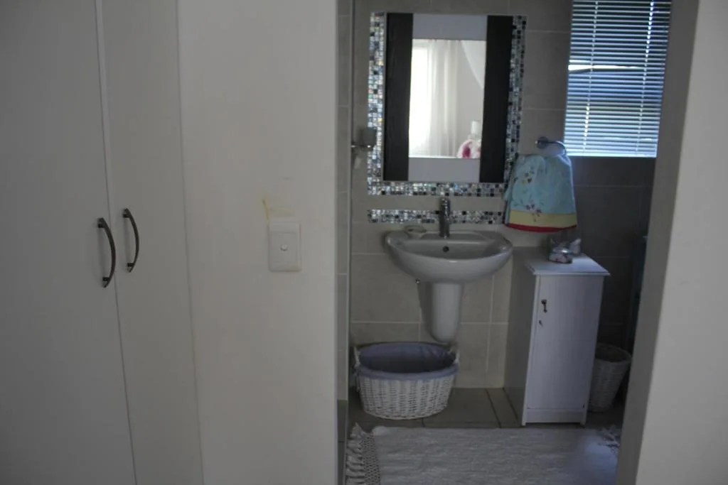 Modern bathroom with pedestal sink, decorative mirror, and storage basket