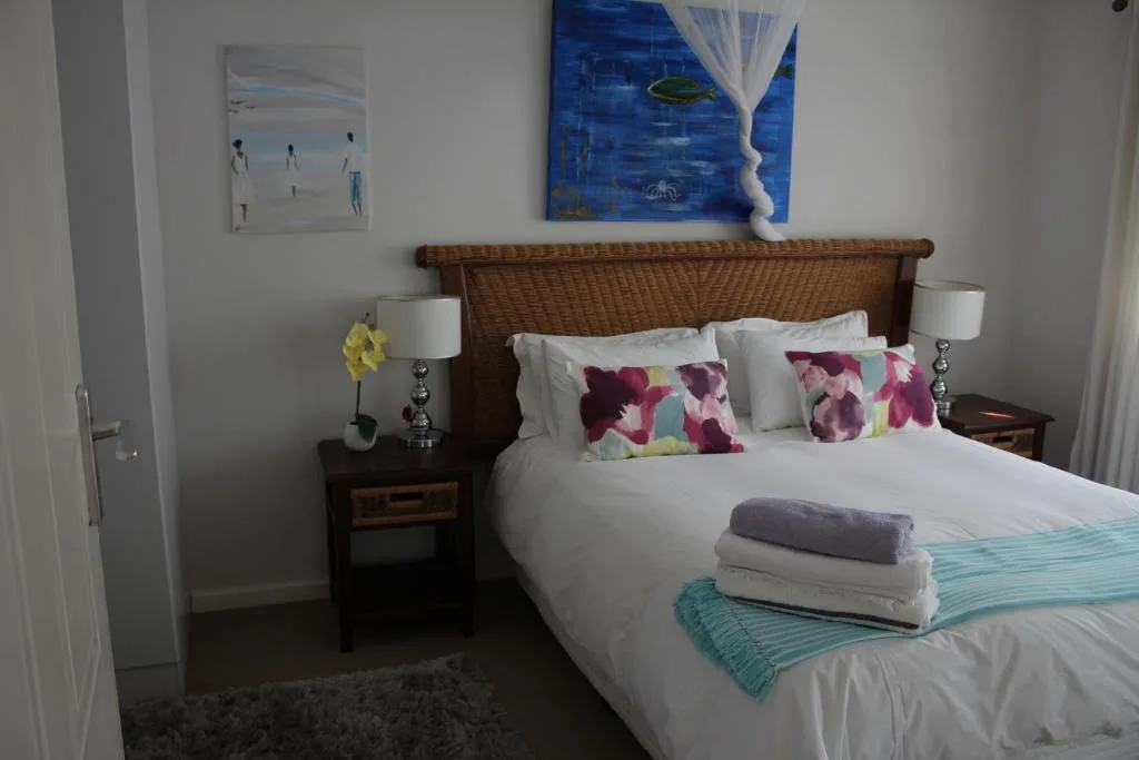 Bedroom with wicker headboard, floral pillows, bedside tables with lamps