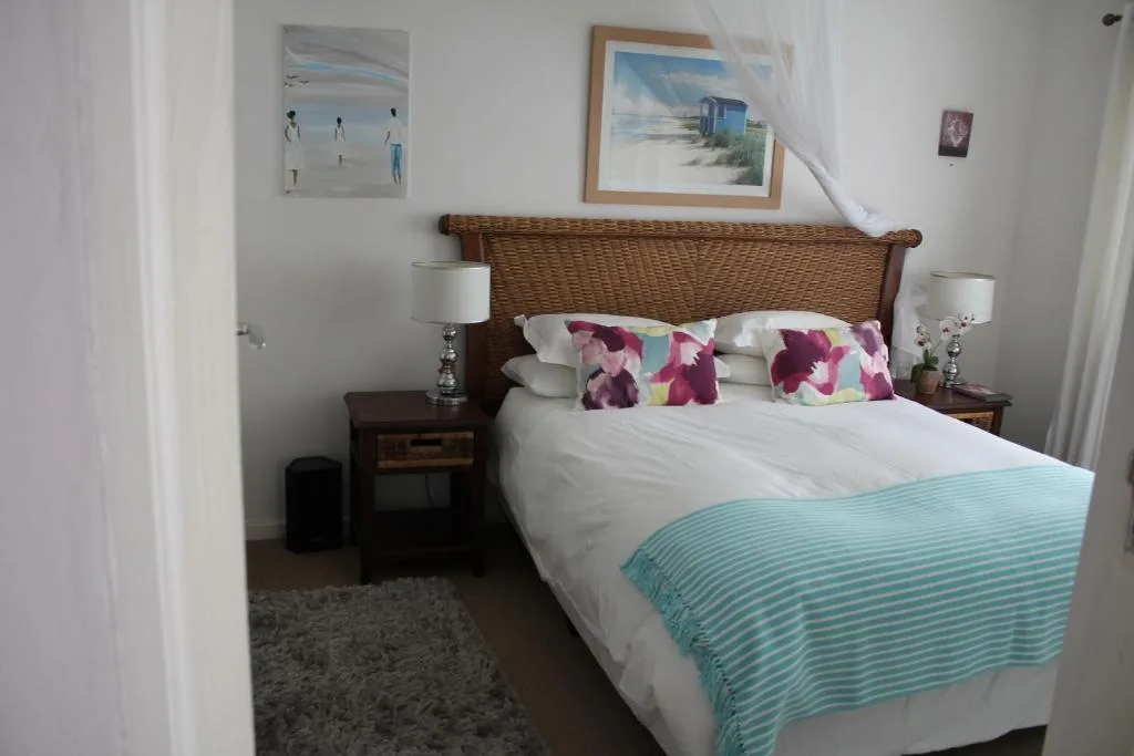 Bedroom with wicker headboard, white bedding, and floral accent pillows