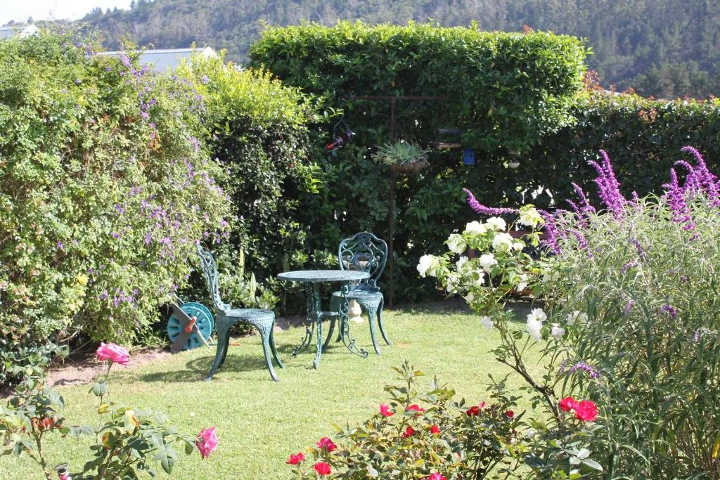 Manicured garden with cast iron table and chairs among blooming flowers