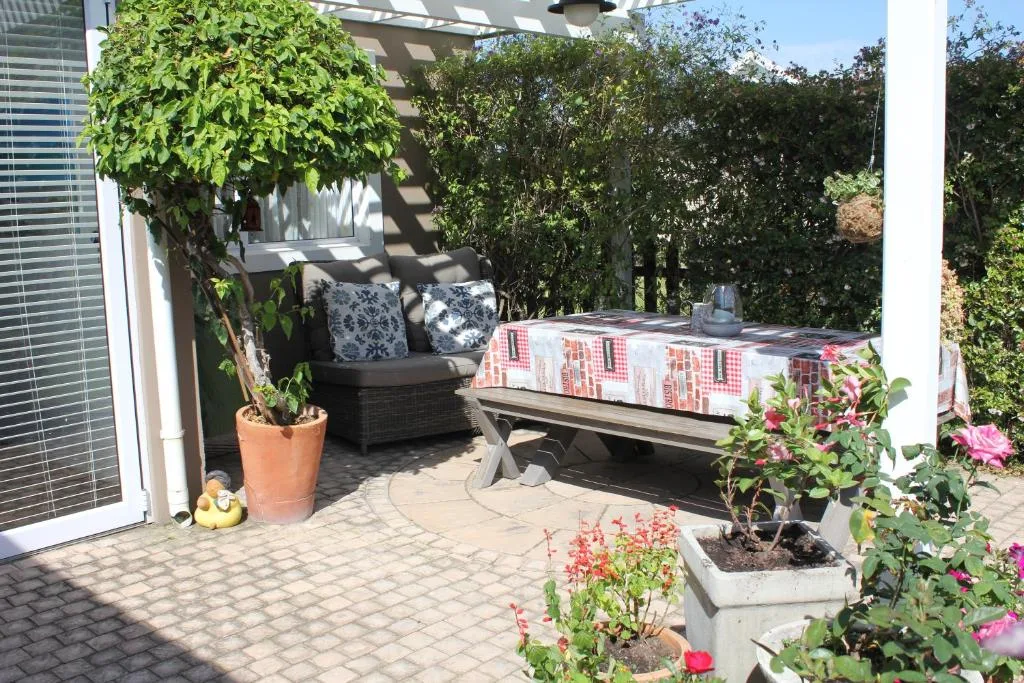 Shaded patio with seating, flowering plants, and pergola structure