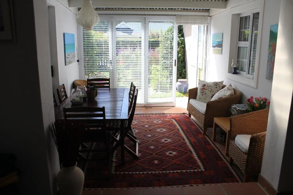 Bright dining area with dark wood table, wicker seating, and garden views