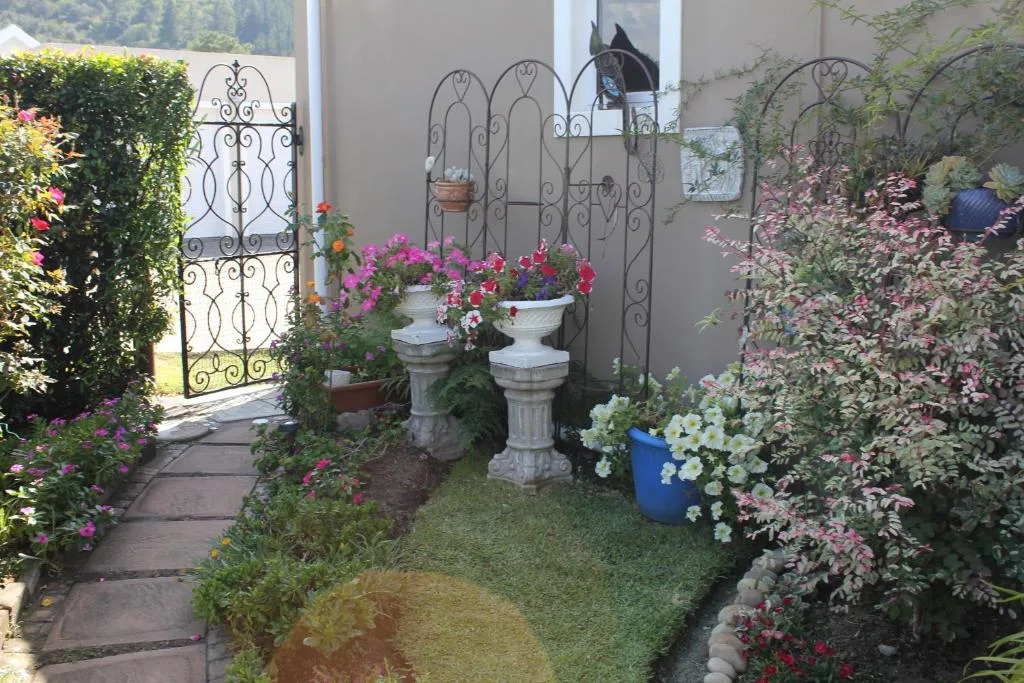Garden pathway with flowering plants and decorative iron gate entrance