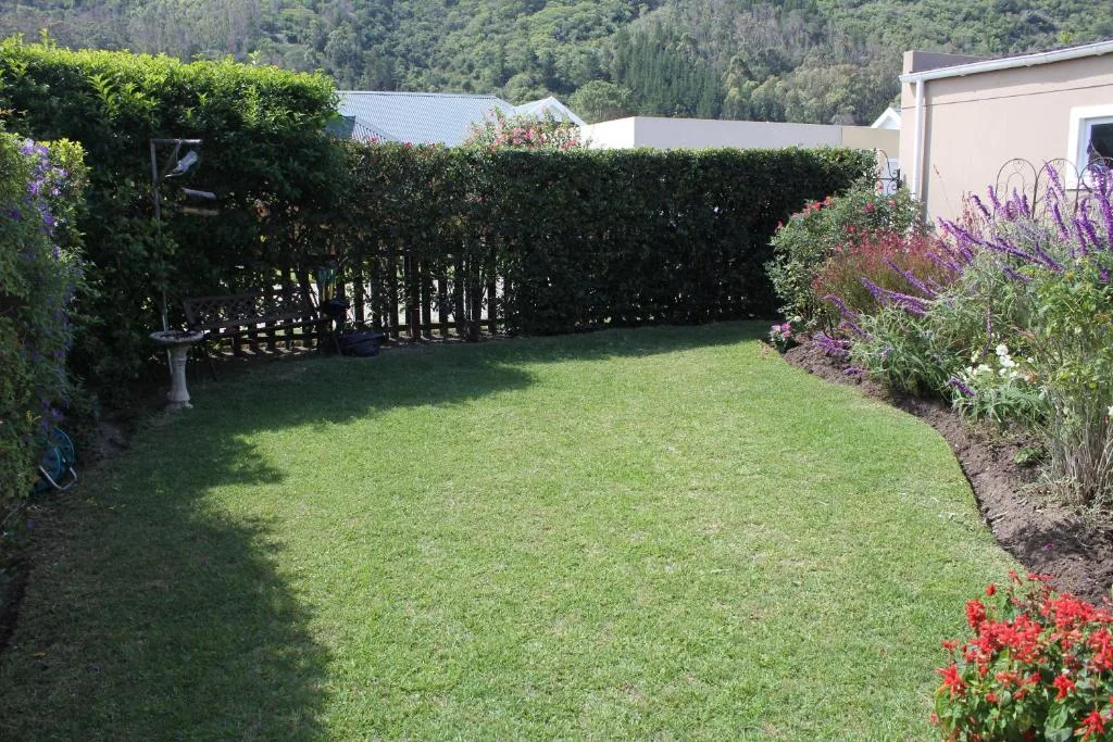 Spacious manicured garden with flowering borders and forested backdrop