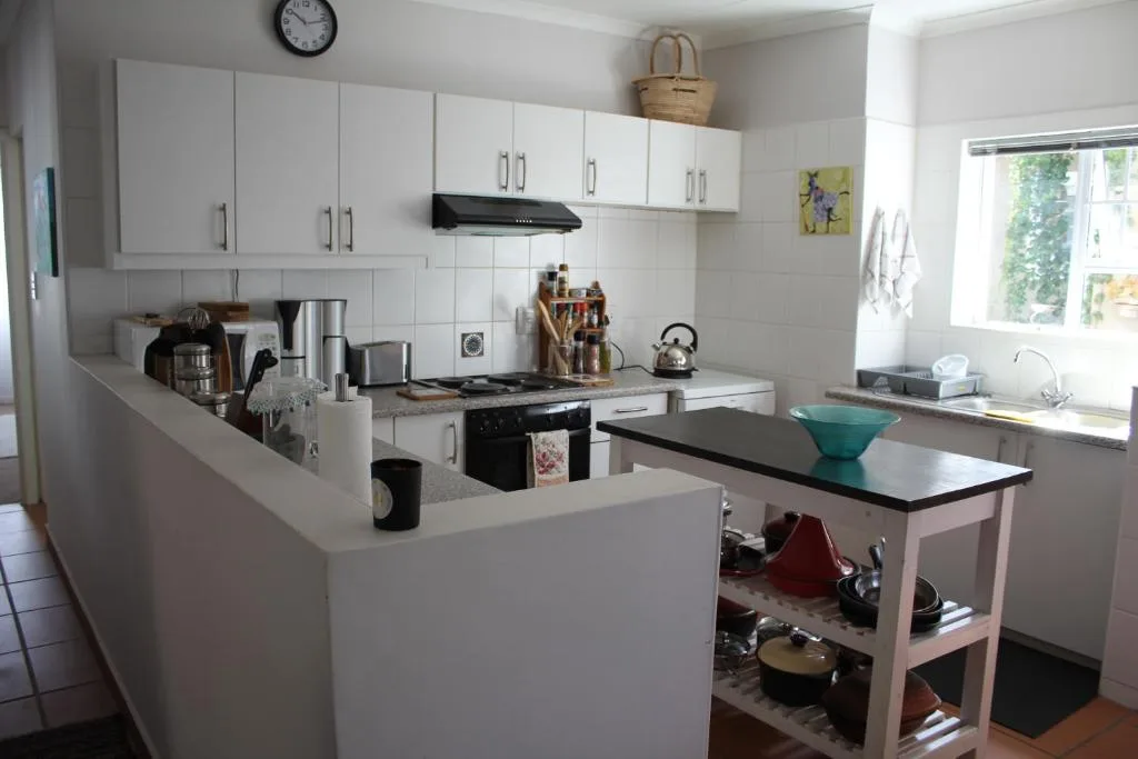 Bright white kitchen with black stove, island bench, and modern appliances