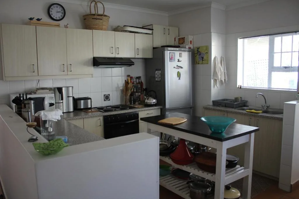 Bright kitchen with cream cabinetry, black stove, and central island bench
