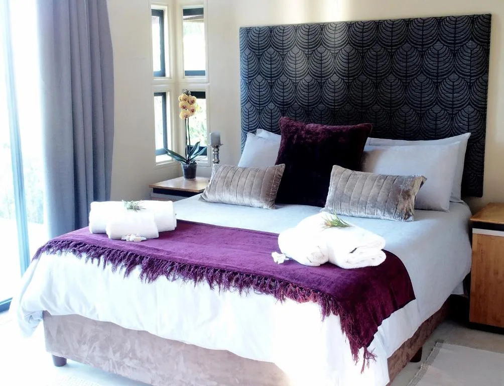 Contemporary bedroom with patterned headboard, purple throw, and fresh white bedding