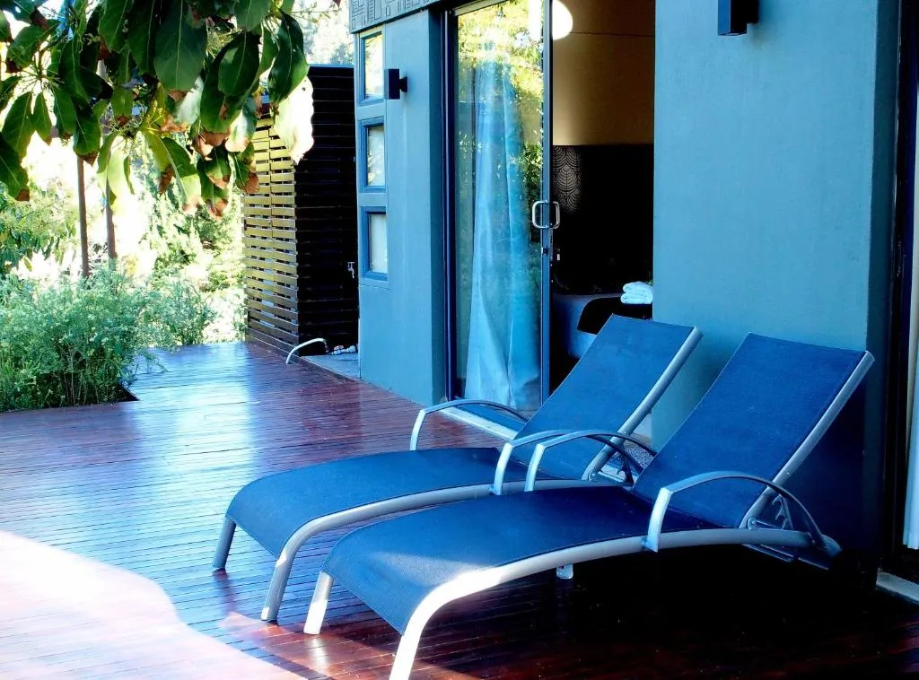 Blue loungers on wooden deck with garden views and cottage entrance