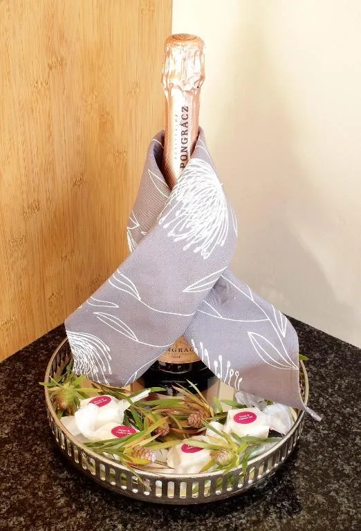 Elegantly wrapped champagne bottle with wine chiller and artisanal treats